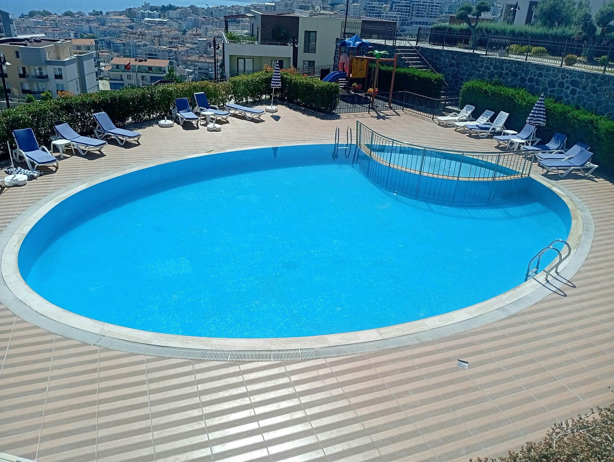 Güneşli havada bakımlı, berrak mavi sulu yuvarlak site havuzu